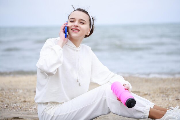 Adorable niña sentada en la playa y hablando por teléfono Foto de alta calidad