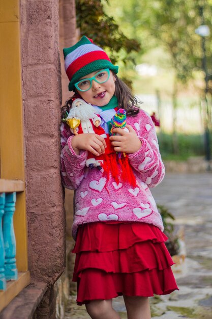 Adorable niña sonriendo y sosteniendo su juguete de Santa Claus