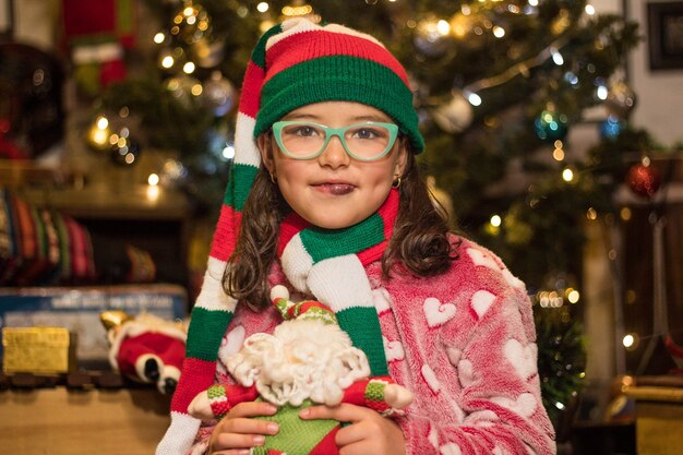 Adorable niña sonriendo y sosteniendo su juguete de Santa Claus