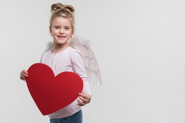 Adorable niña sosteniendo un corazón