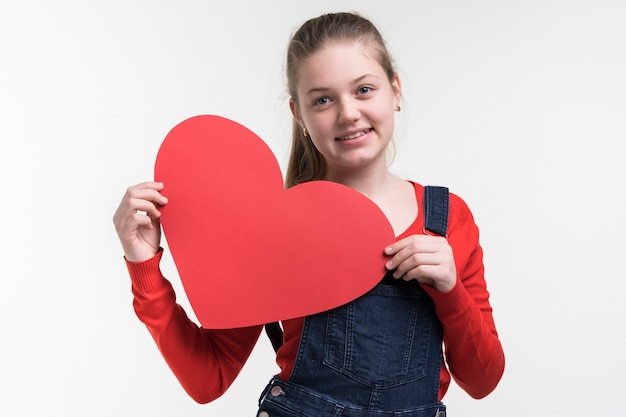 Adorable niña sosteniendo un corazón