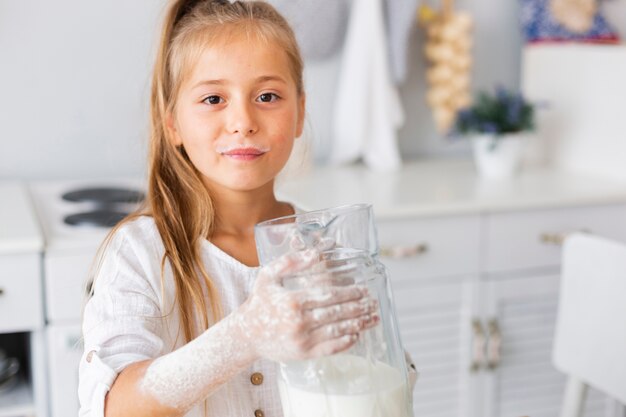 Adorable niña sosteniendo una taza de leche