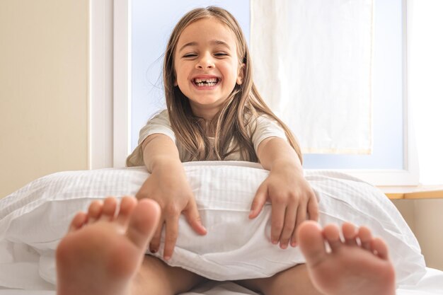 Adorable niña en su cama temprano en la mañana