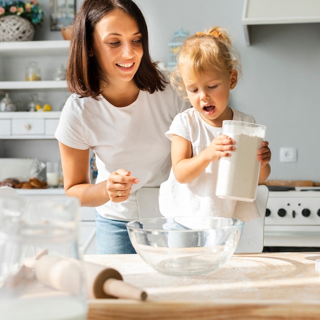 Adorable niña y su madre cocinando juntos