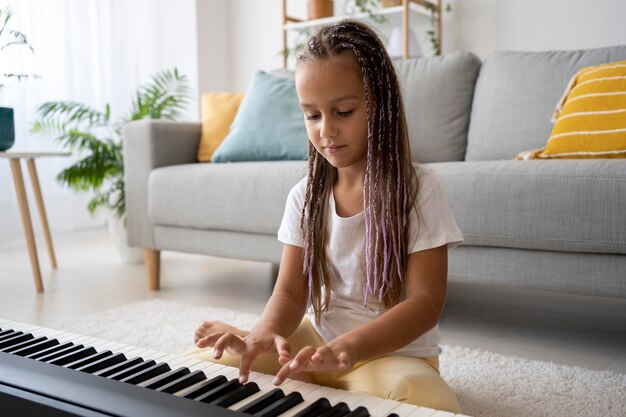 Adorable niña tocando el piano en casa