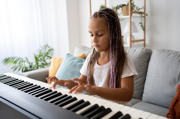 Adorable niña tocando el piano en casa