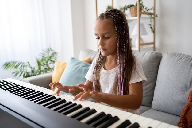 Adorable niña tocando el piano en casa