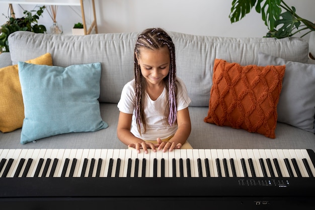 Adorable niña tocando el piano en casa