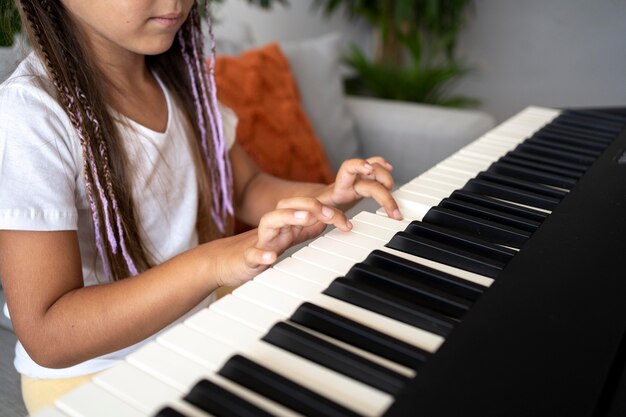 Adorable niña tocando el piano en casa