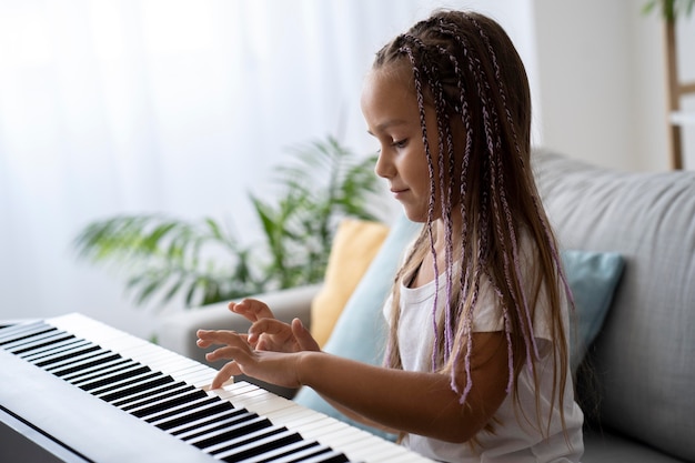 Adorable niña tocando el piano en casa