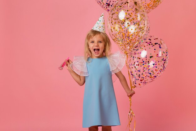 Adorable niña en traje con globos