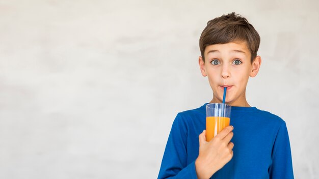 Adorable niño bebiendo un poco de jugo de naranja