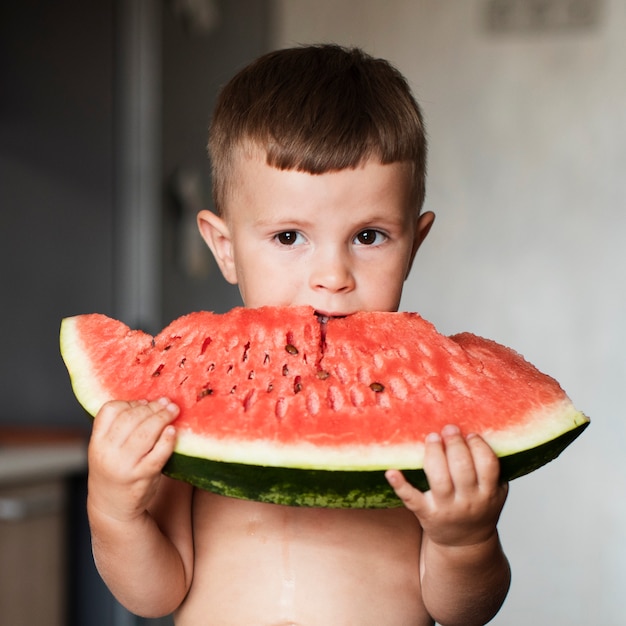 Adorable niño comiendo una rodaja de sandía