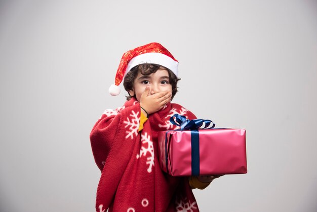 Adorable niño con gorro de Papá Noel con regalo de Navidad