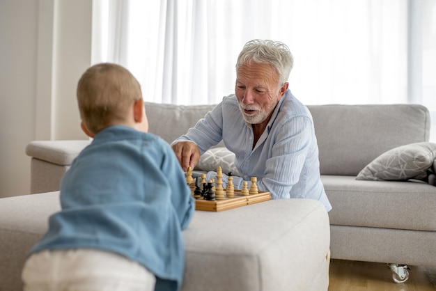 Foto gratuita adorable niño jugando al ajedrez con su abuelo