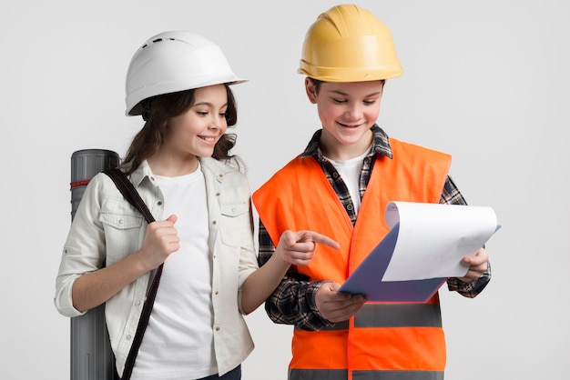 Adorable niño y niña leyendo el plan de construcción