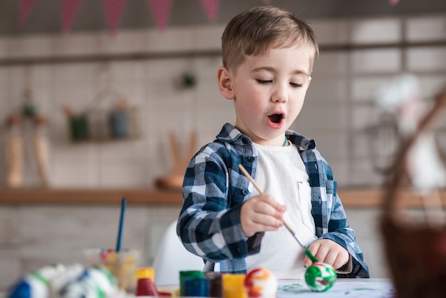 Adorable niño pintando huevos de pascua