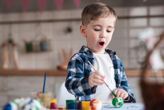 Adorable niño pintando huevos de pascua