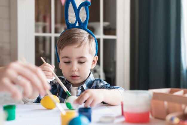 Adorable niño pintando huevos para pascua