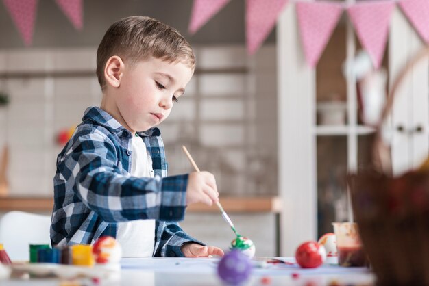 Adorable niño pintando huevos para pascua