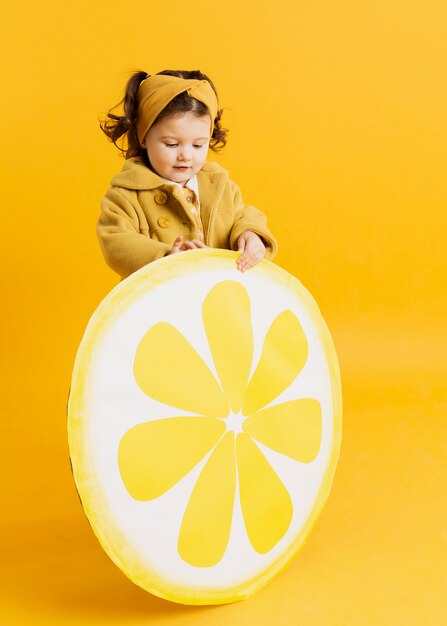 Adorable niño posando mientras sostiene la decoración de rodaja de limón