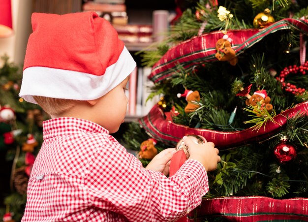 Adorable niño que adorna un árbol de navidad