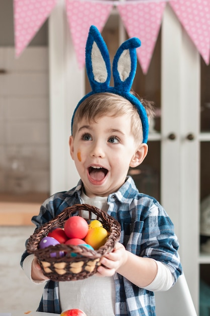Foto gratuita adorable niño sosteniendo la canasta con huevos de pascua
