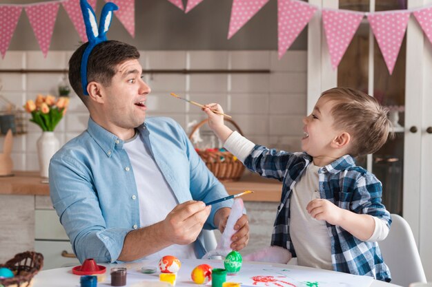 Adorable niño tratando de pintar a su padre