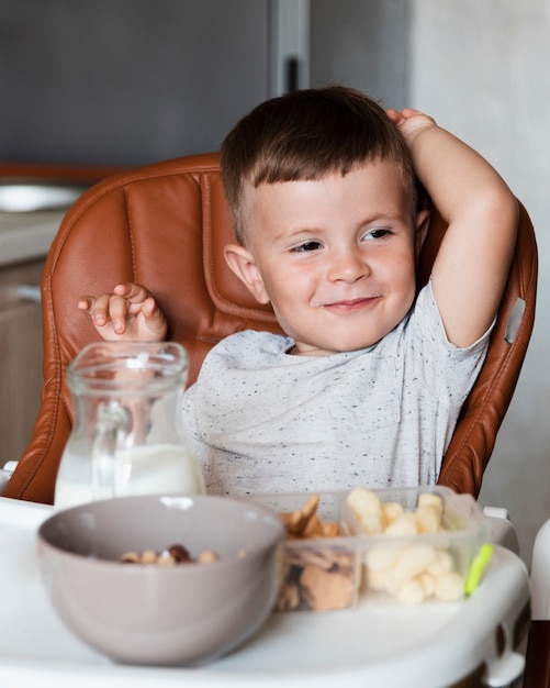 Adorable niño con una variedad de bocadillos en la mesa