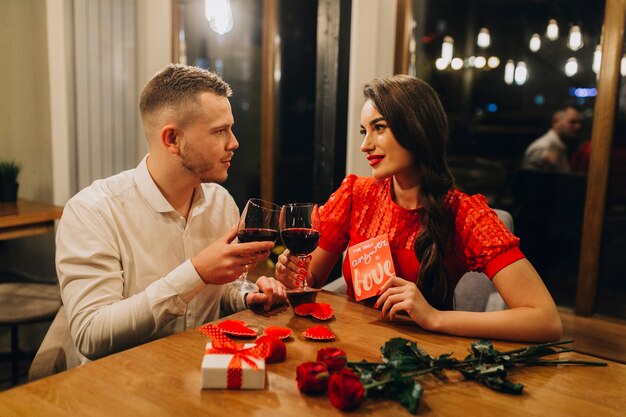 Adorable pareja amorosa con vino en el café