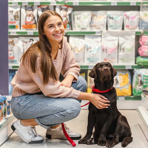 Adorable perro con dueña en la tienda de mascotas