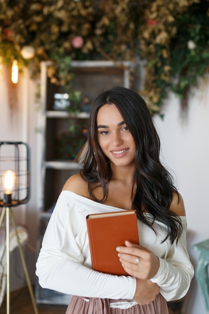 La adorable planificadora de eventos abrazó su libro y sonrió a la cámara Foto de alta calidad