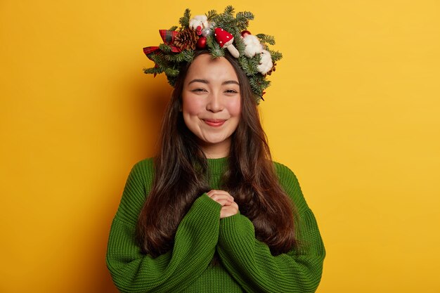 Adorable señorita sonríe agradablemente vistiendo una corona festiva en la cabeza