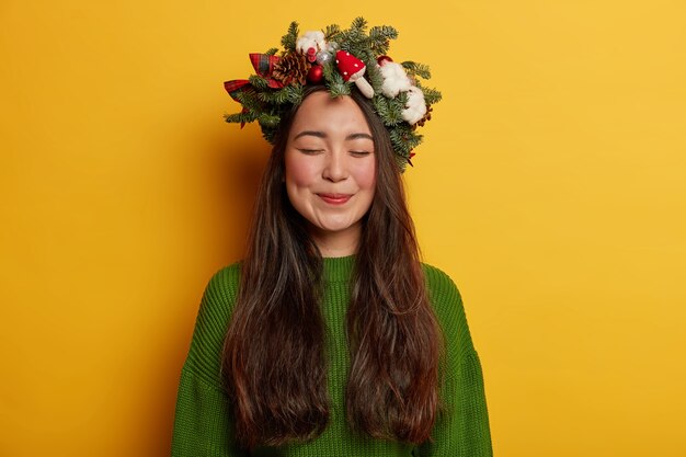 Adorable señorita sonríe agradablemente vistiendo una corona festiva en la cabeza