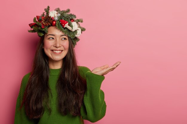 Adorable señorita sonríe agradablemente vistiendo una corona festiva en la cabeza