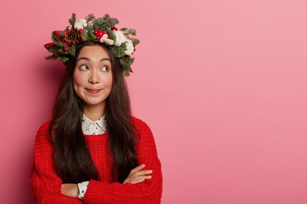 Adorable señorita sonríe agradablemente vistiendo una corona festiva en la cabeza