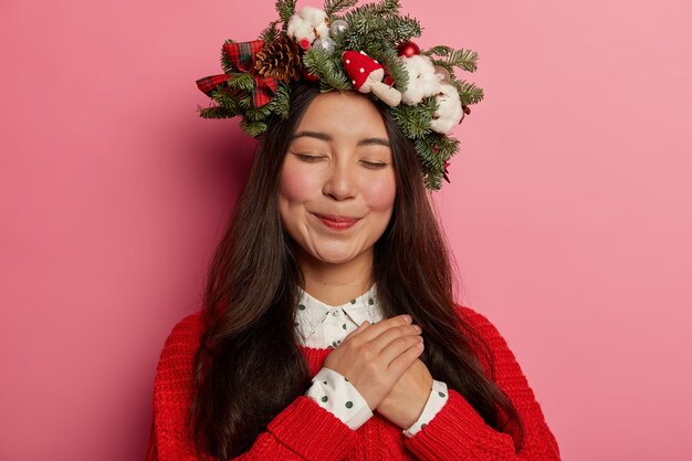 Adorable señorita sonríe agradablemente vistiendo una corona festiva en la cabeza