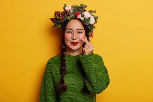 Adorable señorita sonríe agradablemente vistiendo una corona festiva en la cabeza