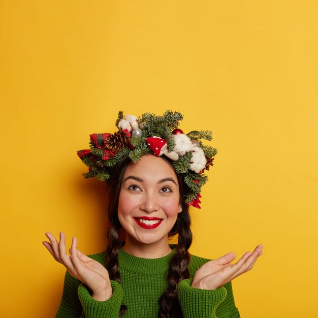 Adorable señorita sonríe agradablemente vistiendo una corona festiva en la cabeza