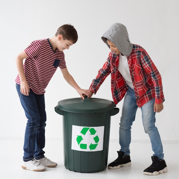 Adorables jóvenes tocando la papelera de reciclaje