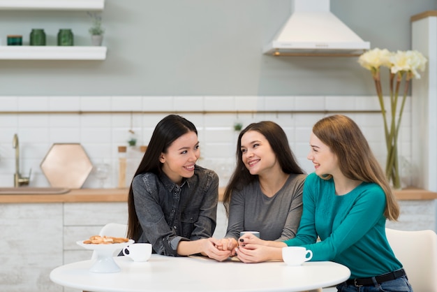 Adorables mujeres jóvenes tomando café en casa