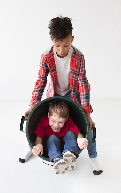 Adorables niños jugando junto con la papelera de reciclaje