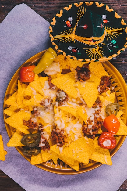 Foto gratuita adornado sabrosos nachos mexicanos en un plato con un sombrero mexicano en la mesa