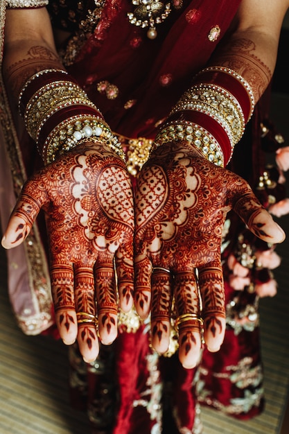 Adorno de corazón indio tradicional en manos coloreadas con henna y pulseras de novia en colores burdeos