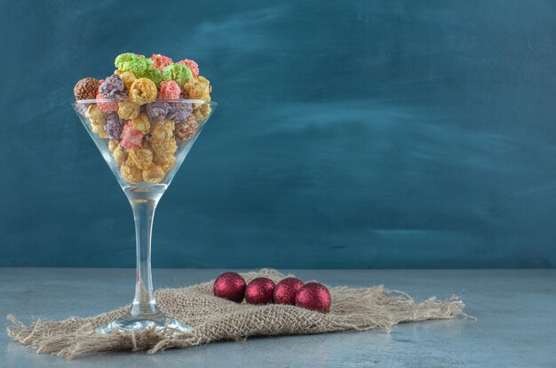 Adornos junto a un soporte de vidrio con palomitas de maíz confitadas sobre superficie de mármol