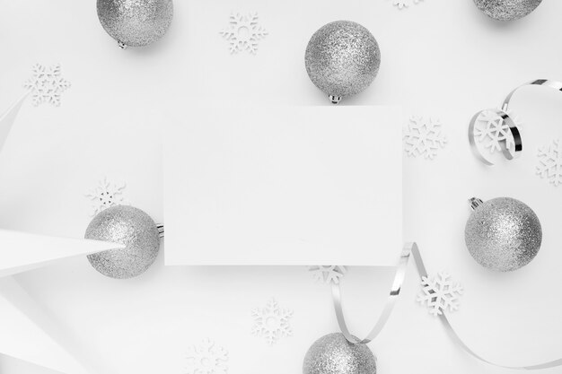 Adornos navideños de plata sobre mesa blanca