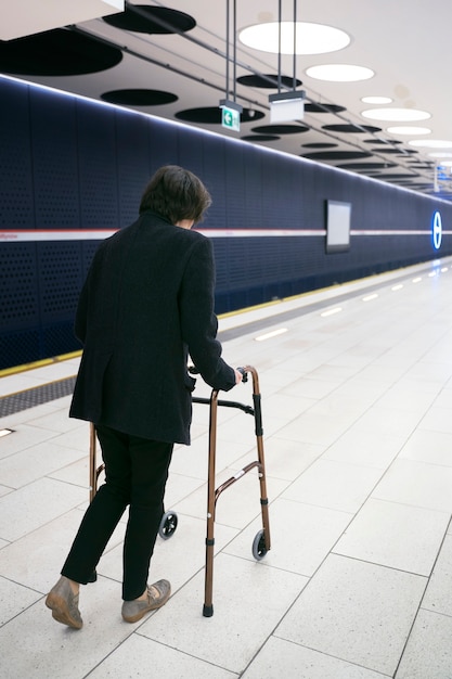 Foto gratuita adulto con andador en la estación de metro tiro completo