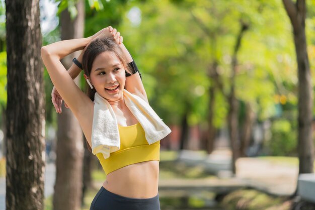 Adulto joven asiático alegre Atractiva y fuerte mañana estirándose antes de correr en el parque Concepto deportivo Estilo de vida saludable Joven corredora de fitness estirándose antes de correr en el parque