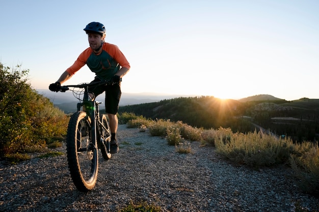 Adulto joven con bicicleta eléctrica en el campo