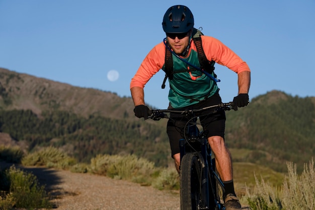 Adulto joven con bicicleta eléctrica en el campo